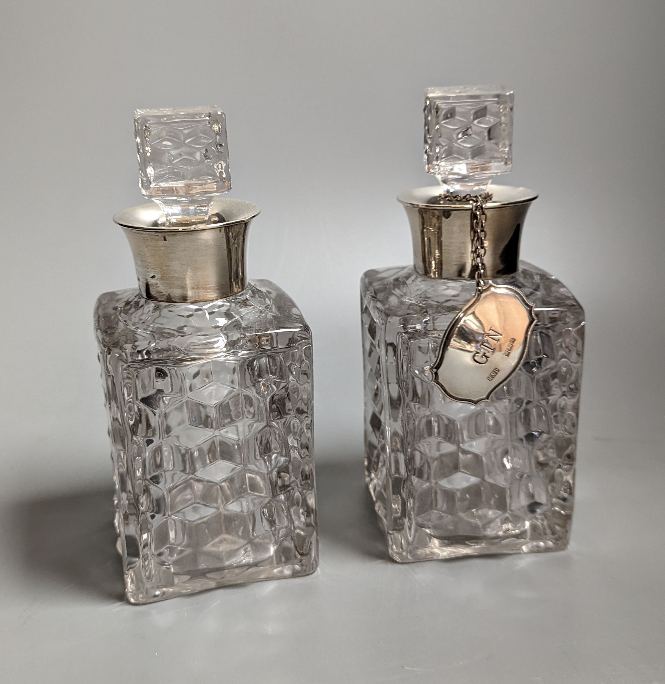 A pair of silver mounted cut glass spirit decanters and a ‘GIN’ spirit label